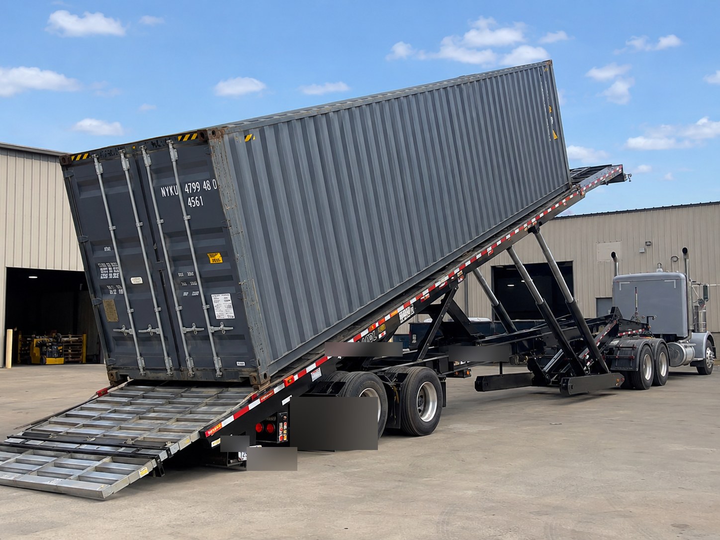 Traveling axle tilt-bed trailer unloading a 40ft container to ground level — OOG / heavy container delivery without crane or forklift